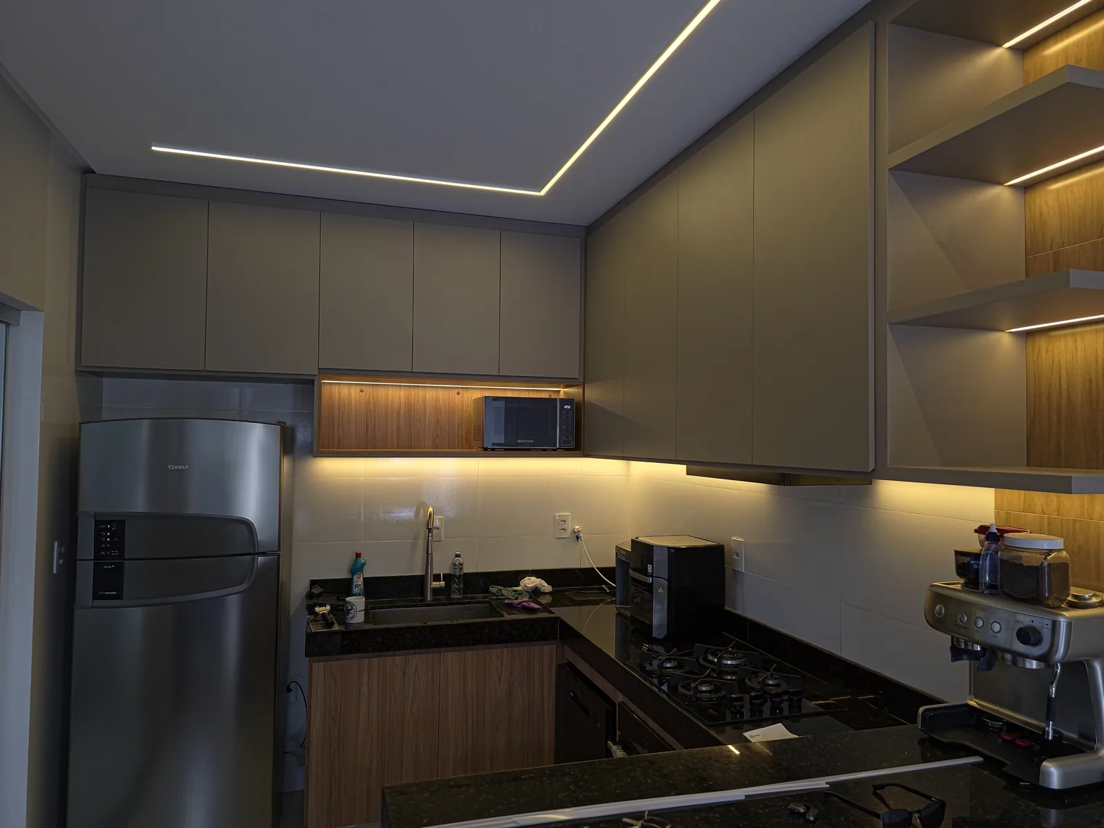 Cozinha planejada em tons de cinza e madeira com iluminação em LED