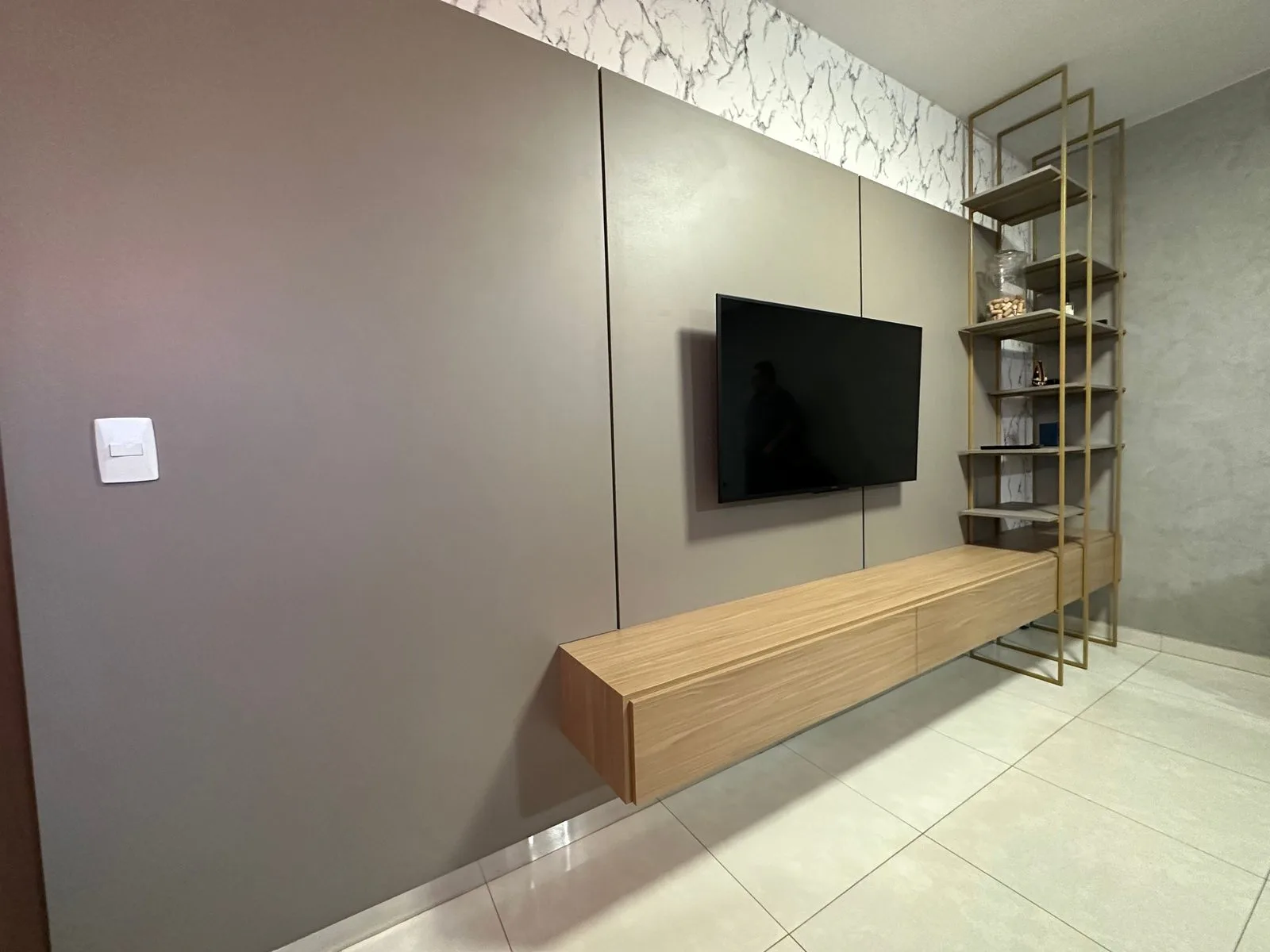 Painel de TV planejado com estante em serralheria dourada